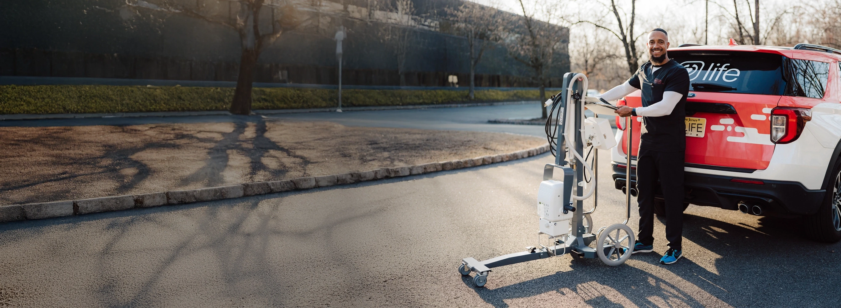 MobileCare technician with portable X-ray machine standing next to branded vehicle, providing in-home imaging services.